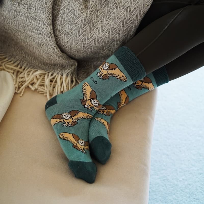 Bamboo socks with barn owl pattern worn by a person sitting on a couch.