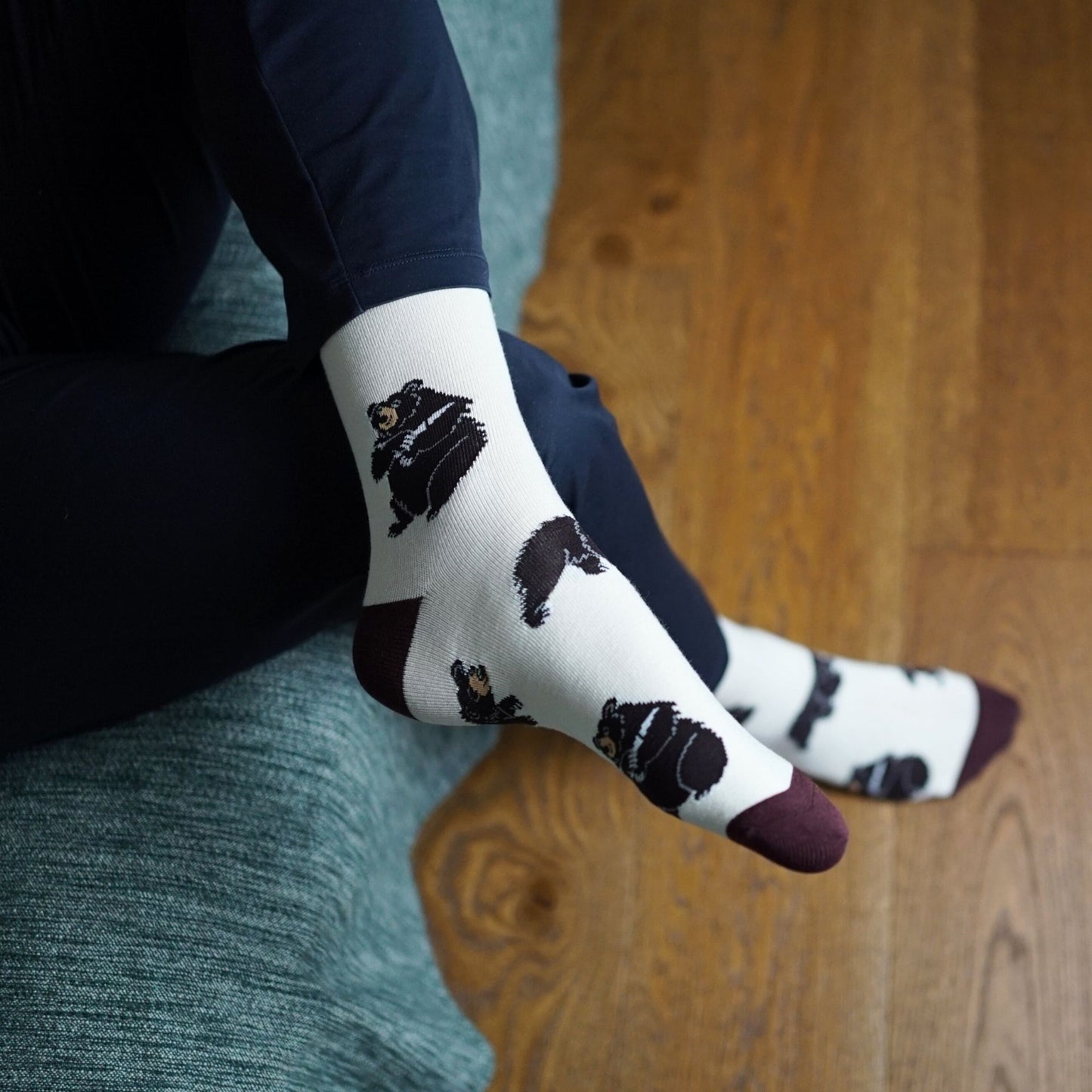 Person wearing socks with black bear pattern on a wooden floor