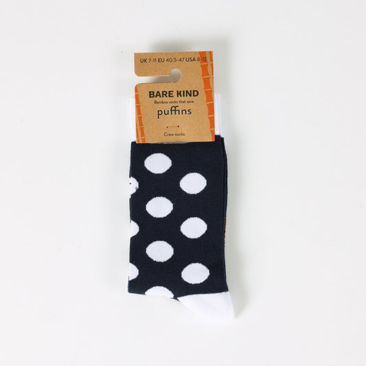 Black socks with white polka dots and a Bare Kind packaging label on a light gray background