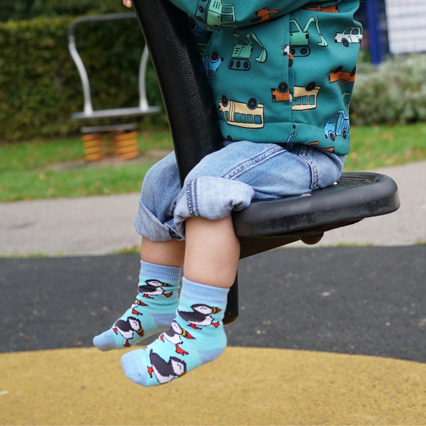 Child wearing puffin socks on a playground swing set
