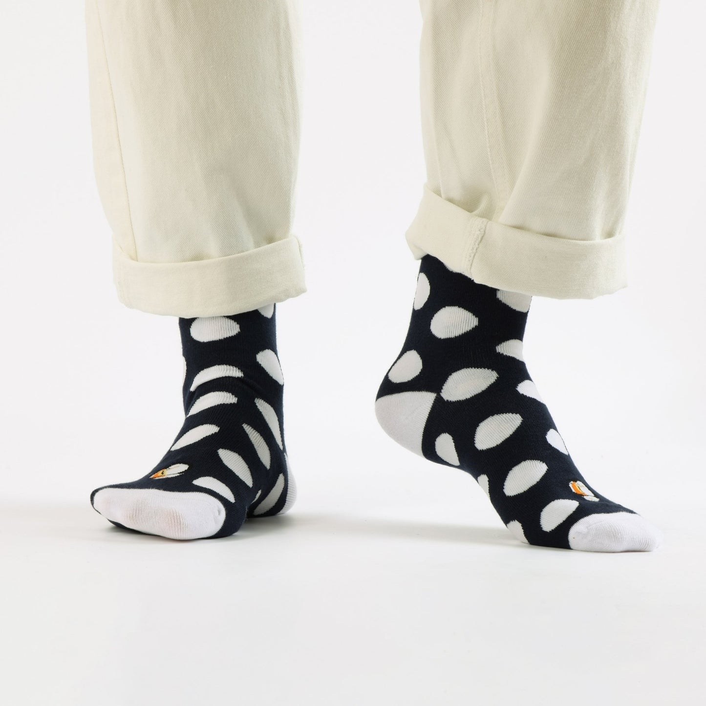 Black socks with white polka dots worn with beige pants on a white background