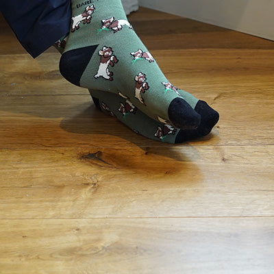 Green socks with goat pattern worn on a wooden floor