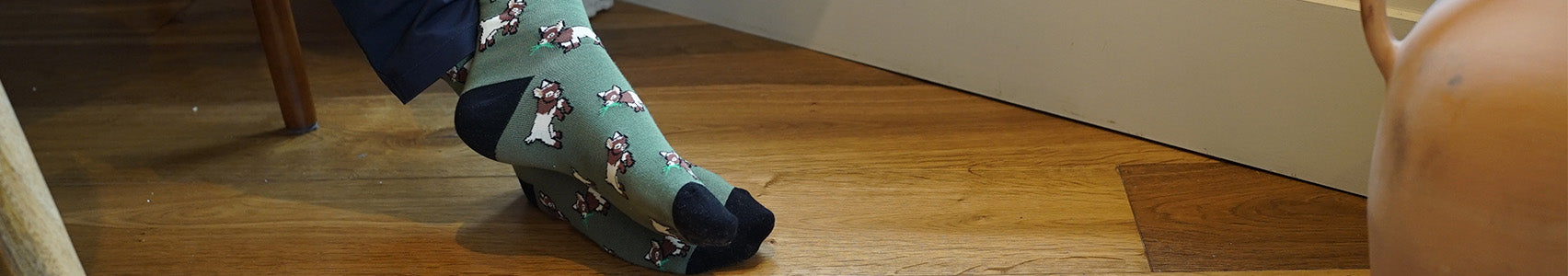 Green socks with goat pattern worn on a wooden floor
