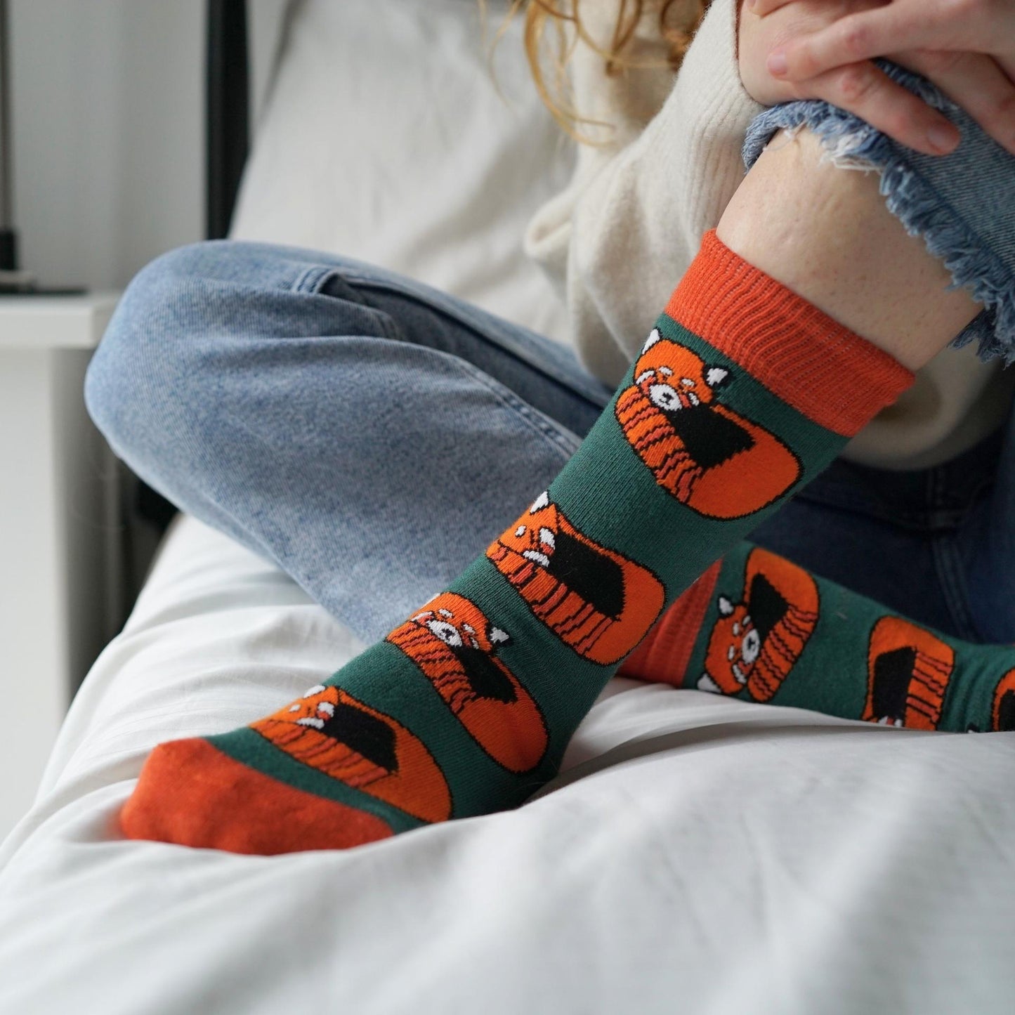 Person wearing socks with red panda designs on a white surface