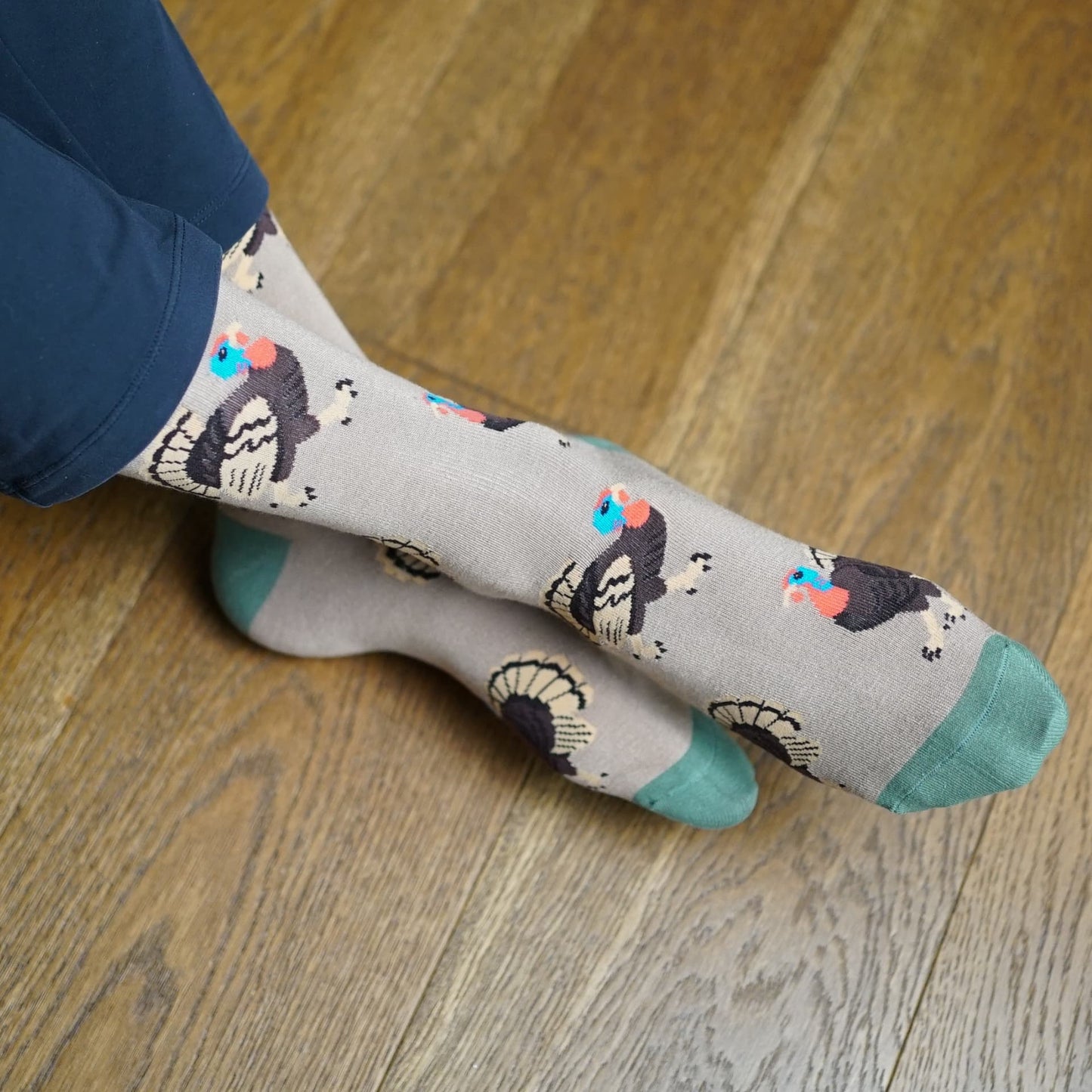 Person wearing socks with Turkey design sitting on a couch.