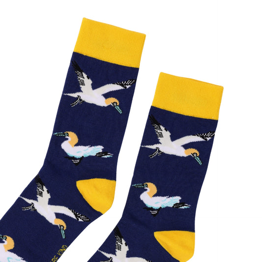 A pair of navy blue crew socks featuring a pattern of flying gannets in white, yellow, and light blue, with bright yellow cuffs, heels, and toes, displayed on a clean white background.