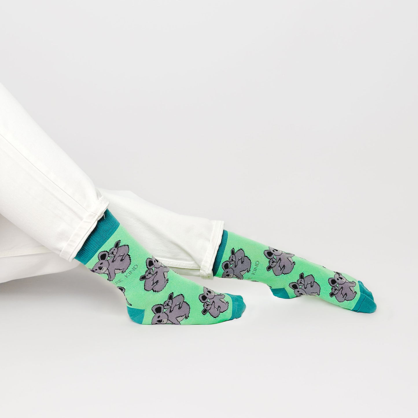 sitting model with feet outstretched wearing green koala socks