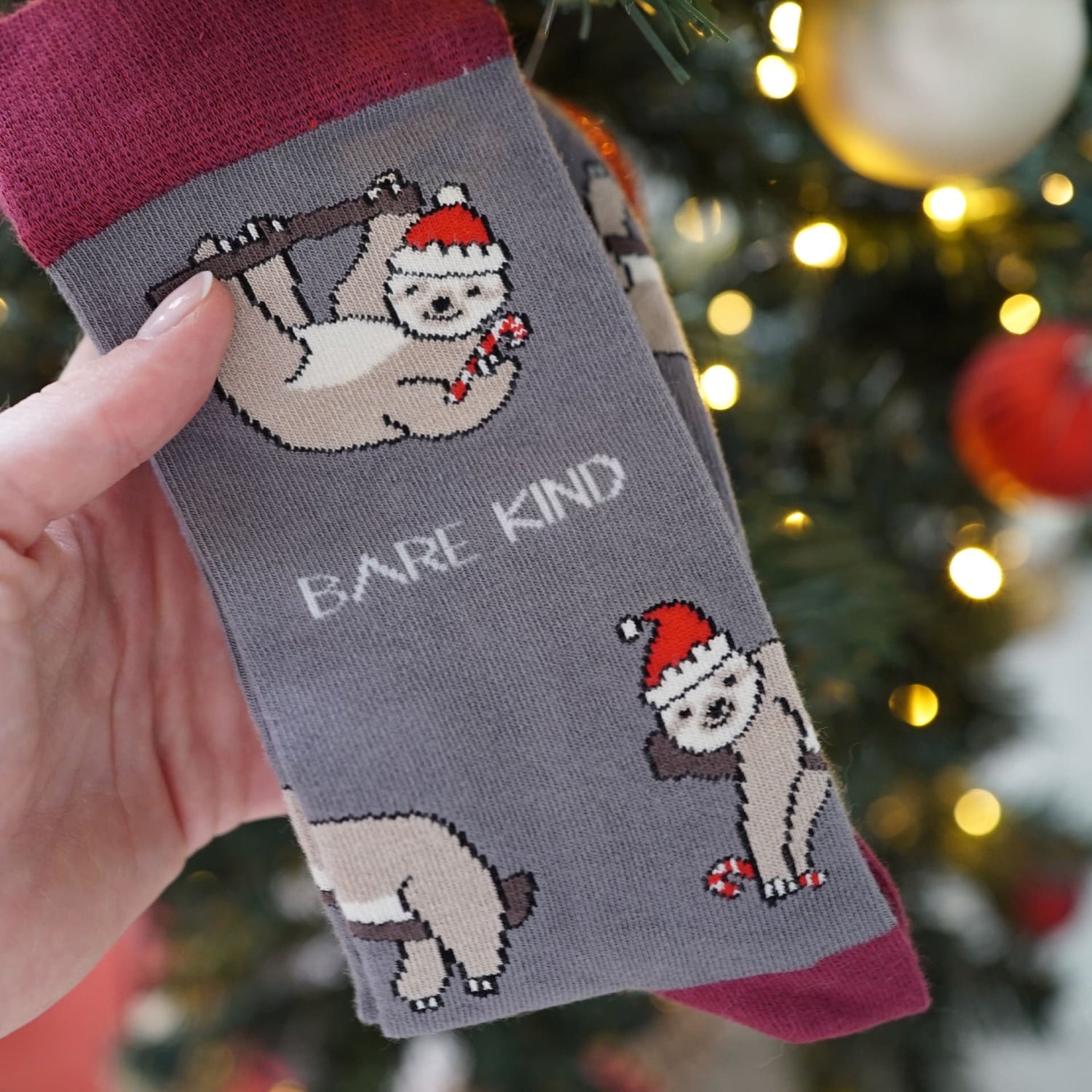 grey red Christmas sloth bamboo socks in front of Christmas tree