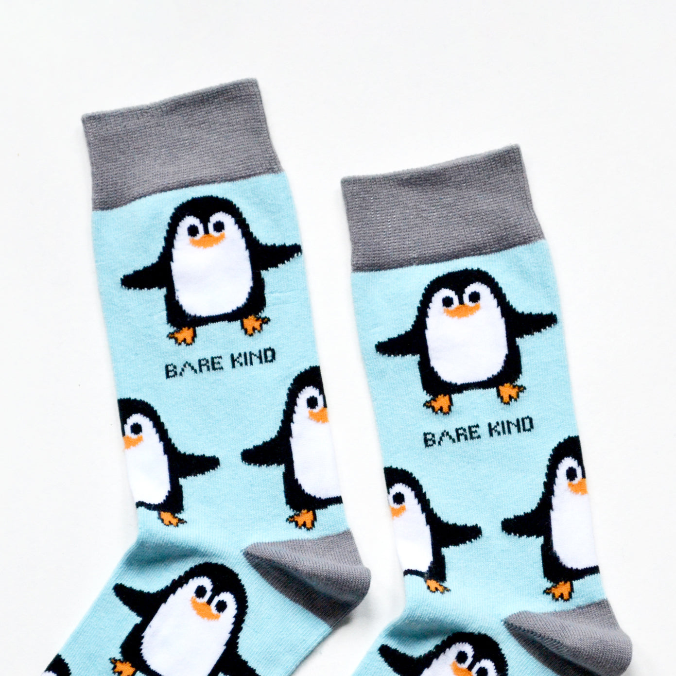 cuff closeup flat lay of sky blue bamboo socks with woven penguin design