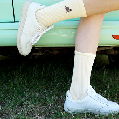 Model wearing yellow ribbed pastel socks with otter motif embroidered on cuff