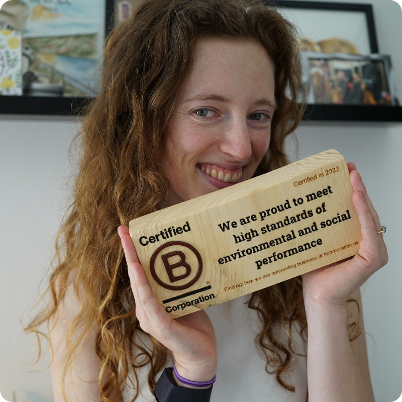 Person holding a wooden B Corp certification plaque