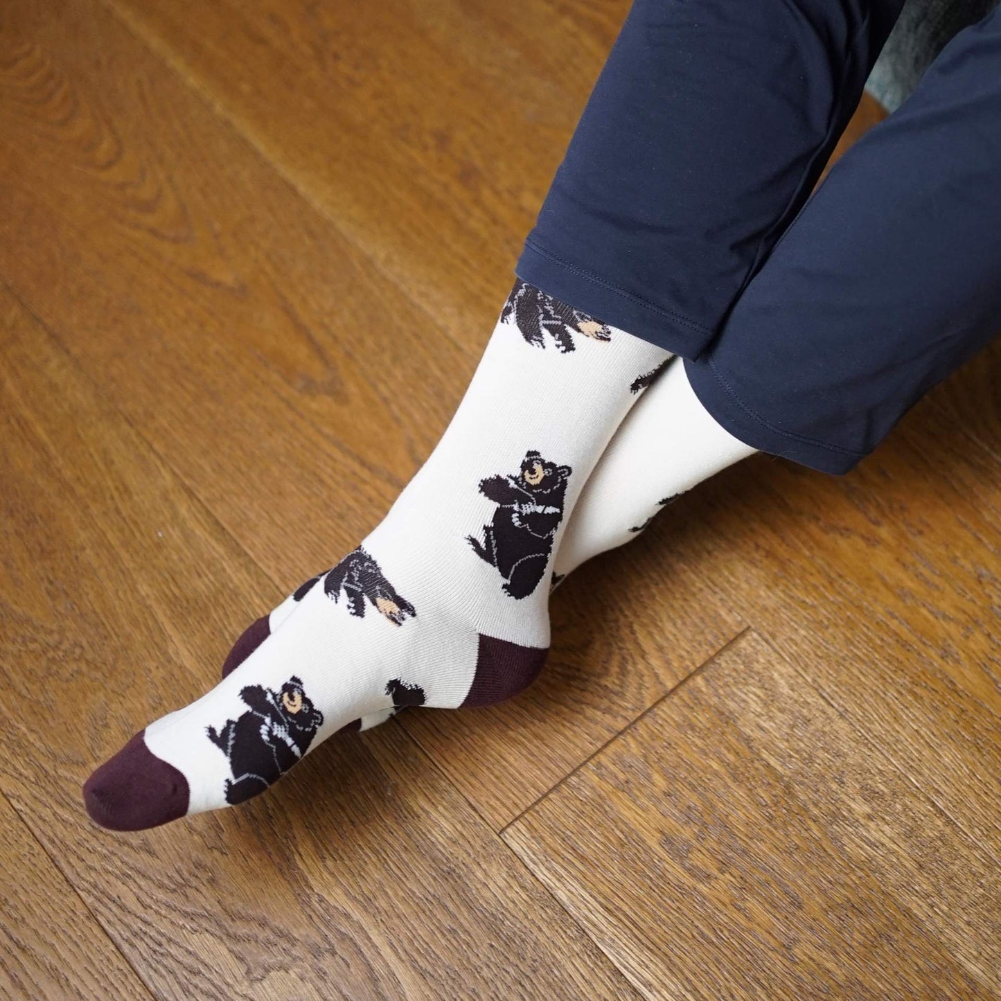 Person wearing socks with black bear pattern on a wooden floor
