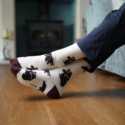 Person wearing socks with black bear pattern on a wooden floor
