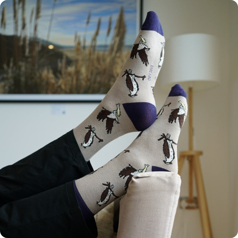 Person wearing socks with otter design in a room with a lamp and painting.
