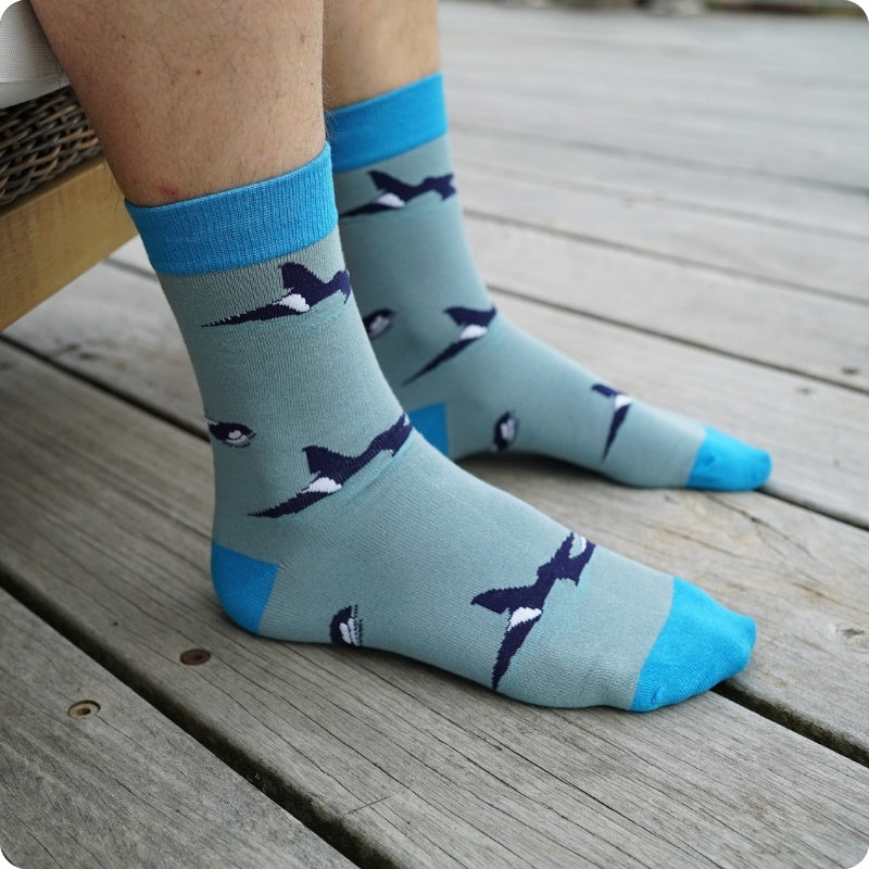 Light blue socks with orca design on a wooden floor