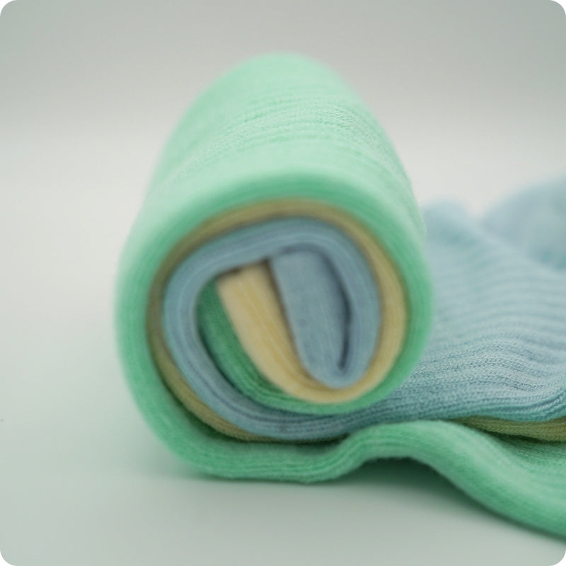 Rolled-up green and blue socks on a white background
