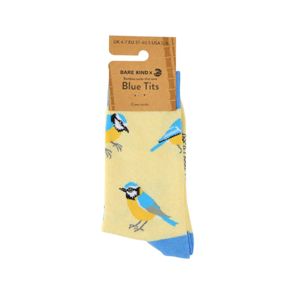 A pair of Bare Kind x Blue Tits bamboo crew socks in pale yellow, featuring a pattern of blue tits and blue toe caps, shown on a white background with its cardboard hanger.