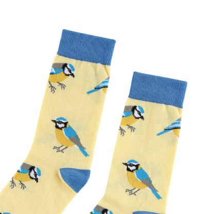 A pair of light yellow crew socks with a blue and yellow bird pattern, featuring solid blue ribbed cuffs and heels, displayed on a white background.