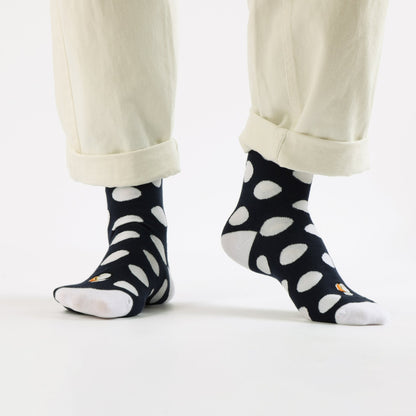 Black socks with white polka dots worn with beige pants on a white background