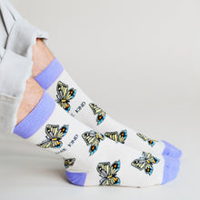 side profile view of sitting model wearing cream and lavender butterfly bamboo socks