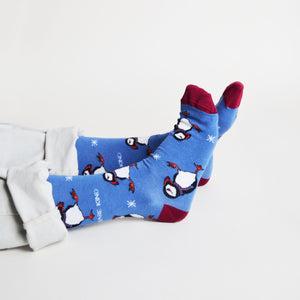 sitting model with feet outstretched wearing christmas puffin socks, side view