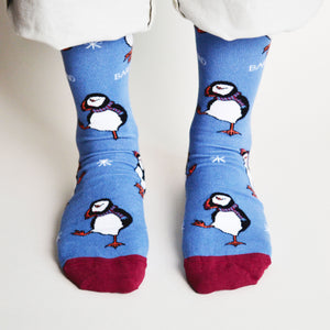 standing model wearing cobalt and maroon christmas puffin socks, front view