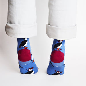 rear view of standing model on tip toes wearing cobalt christmas socks with puffin design
