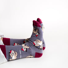 sitting model wearing christmas sloth socks, with feet oustretched, side view