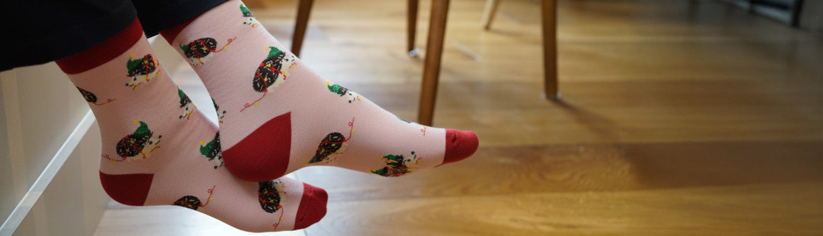 Person wearing socks with a pattern of christmas hedgehogs
