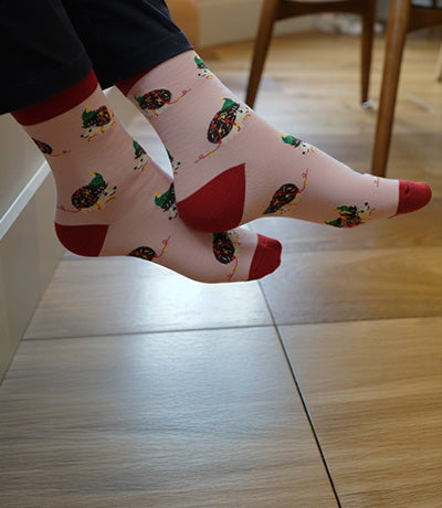 Person wearing socks with a pattern of christmas hedgehogs