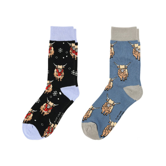 Two pairs of crew socks displayed side by side on a plain white background. The left pair is black with a light blue cuff and toe, decorated with a pattern of highland cows in red and beige.