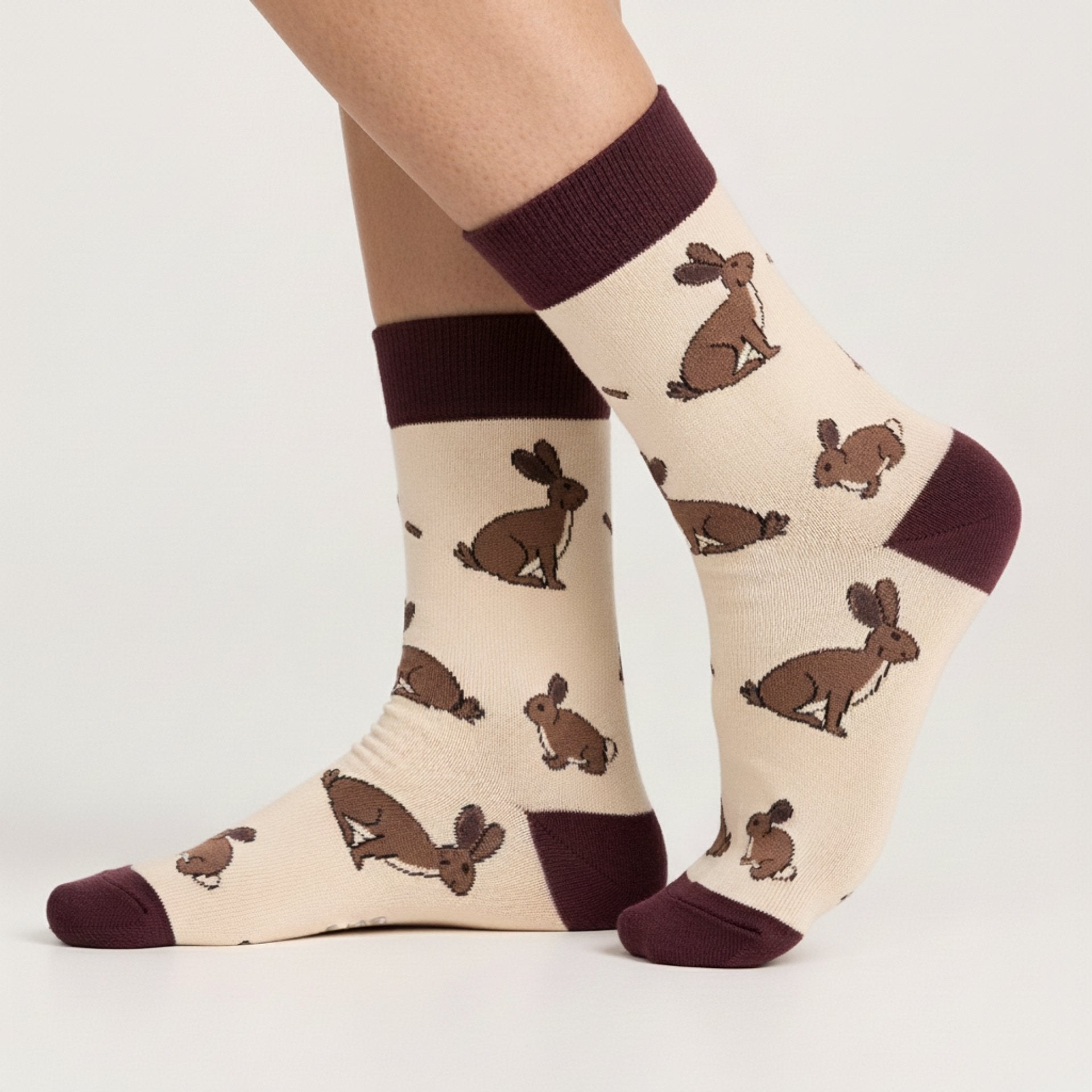 Beige socks with brown hare patterns worn by a person on a light gray background