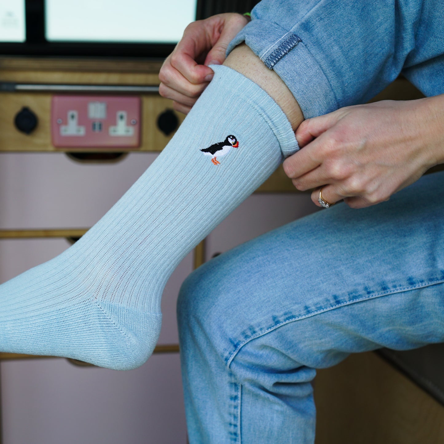 Model wearing pastel blue socks with penguin small motif design embroidered on cuff