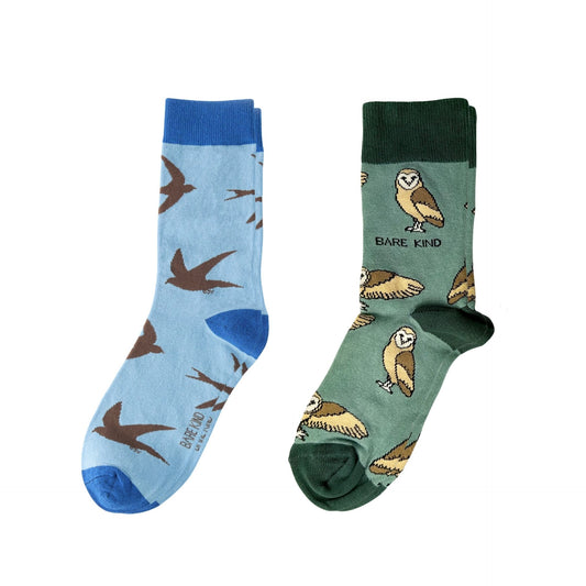 Two pairs of socks, one blue with swift patterns and one green with owl patterns, on a white background.