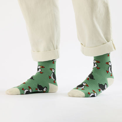 Green socks with penguin design worn by a person on a white background