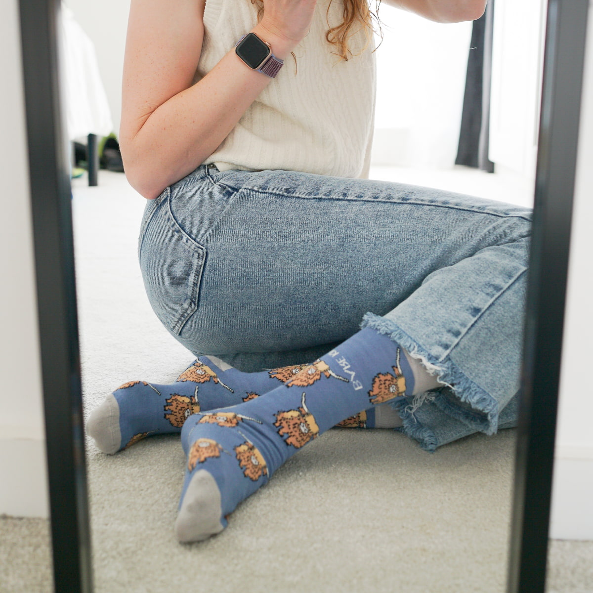 Model wearing highland cows bamboo socks in front of mirror