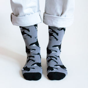 standing model wearing black bamboo socks with an orca design 