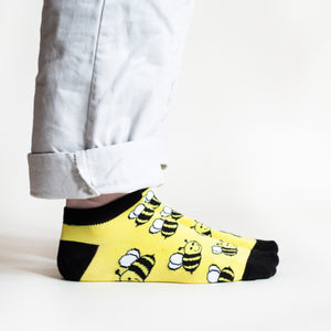 side profile of standing model wearing black and yellow ankle socks with bee design