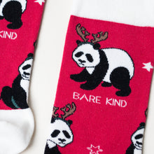closeup flat lay of red and white bamboo christmas socks featuring a panda wearing a reindeer headdress