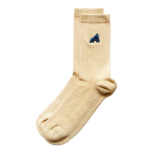minimalist flat lay of pastel yellow ribbed bamboo socks with embroidered gorilla motif on the cuff