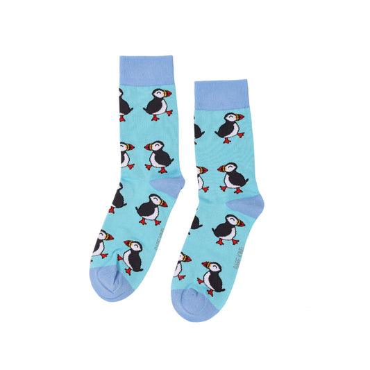 A pair of light blue crew socks featuring a repeating pattern of cartoon puffins, shown against a plain white background.