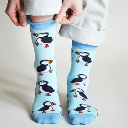 Light blue socks with puffin design worn by a person on a plain background