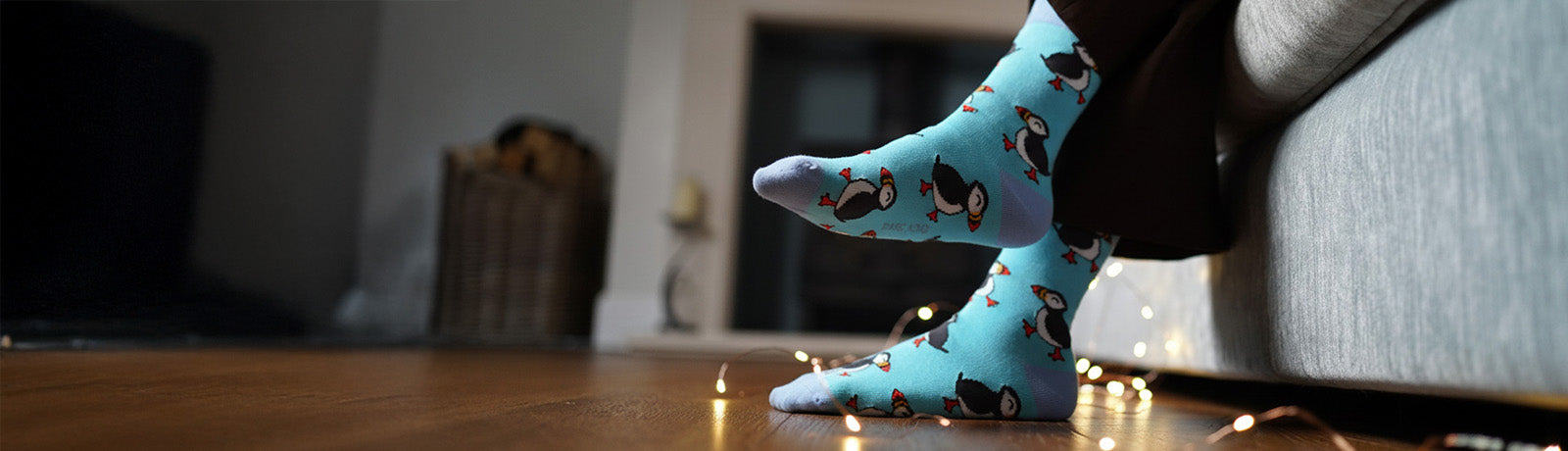 Blue puffin socks worn by a person on a wooden floor.