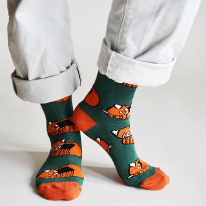 Person wearing socks with red panda patterns on a light background