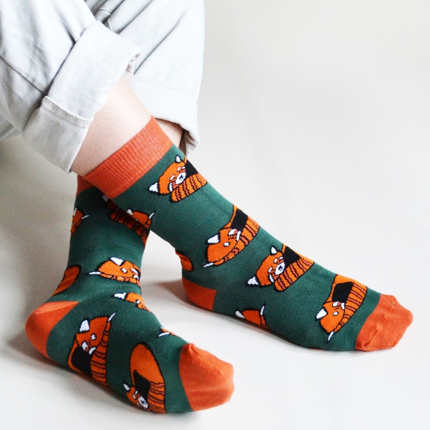 Person wearing socks with red panda pattern on a light background