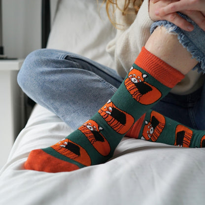 Person wearing socks with red panda designs on a white surface