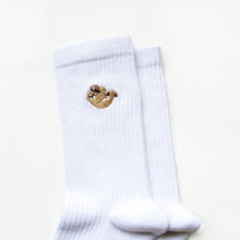 cuff closeup of essential white ribbed bamboo socks featuring an embroidered sloth motif on the cuff