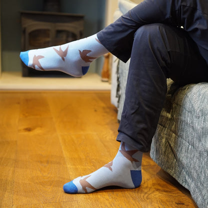 Person wearing swift socks sitting on a couch with wooden floor.