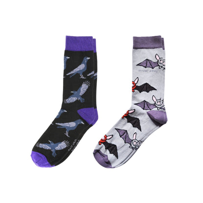 Two pairs of socks with raven and bat patterns on a white background