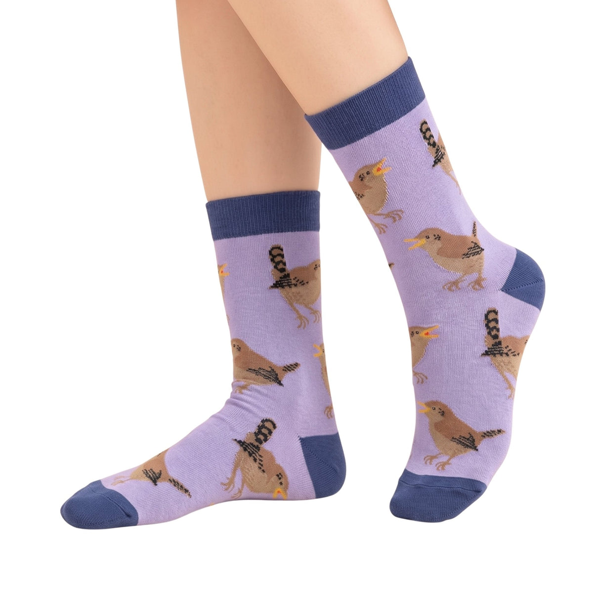A pair of crew socks worn on feet, featuring a light purple background with a repeating pattern of small brown birds and dark blue ribbed cuffs, heels, and toes, shown against a plain white background.